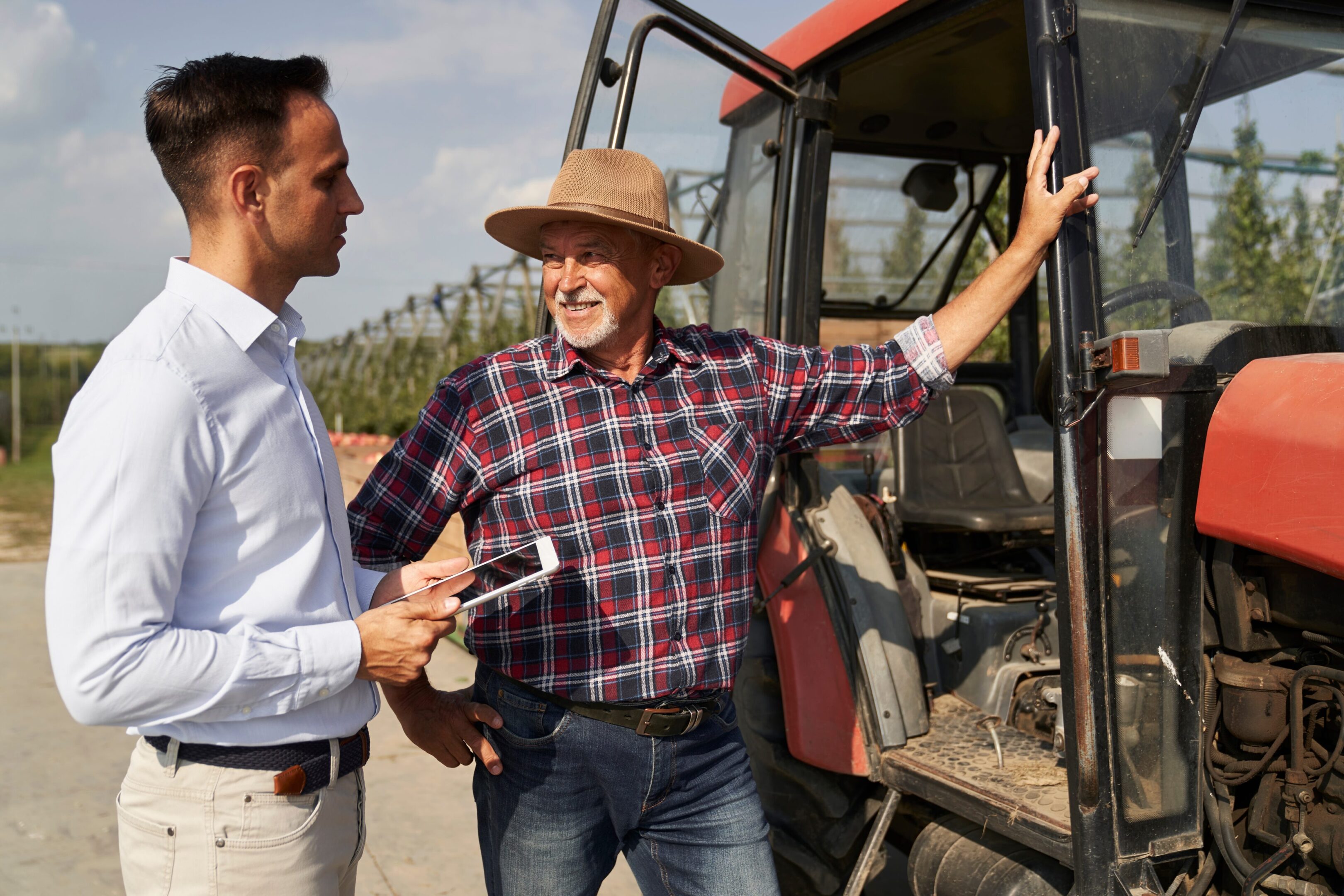 Senior,Farmer,And,Sales,Representative,Next,To,Tractor,Talking,Over